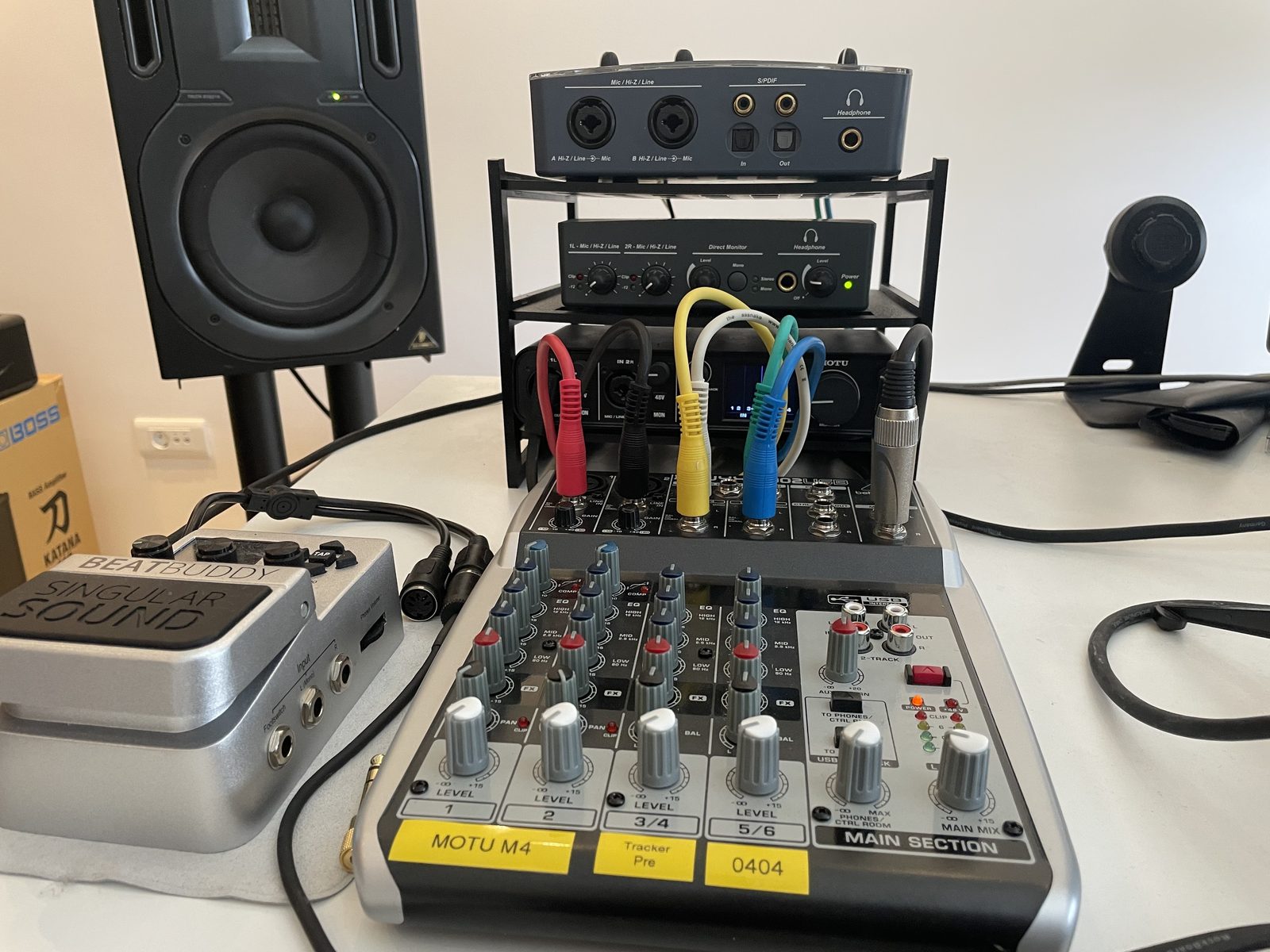 The interface rack standing behind a small mixer, coloured patch cables running from each interface into mixer channels labelled MOTU M4, Tracker Pre and 0404