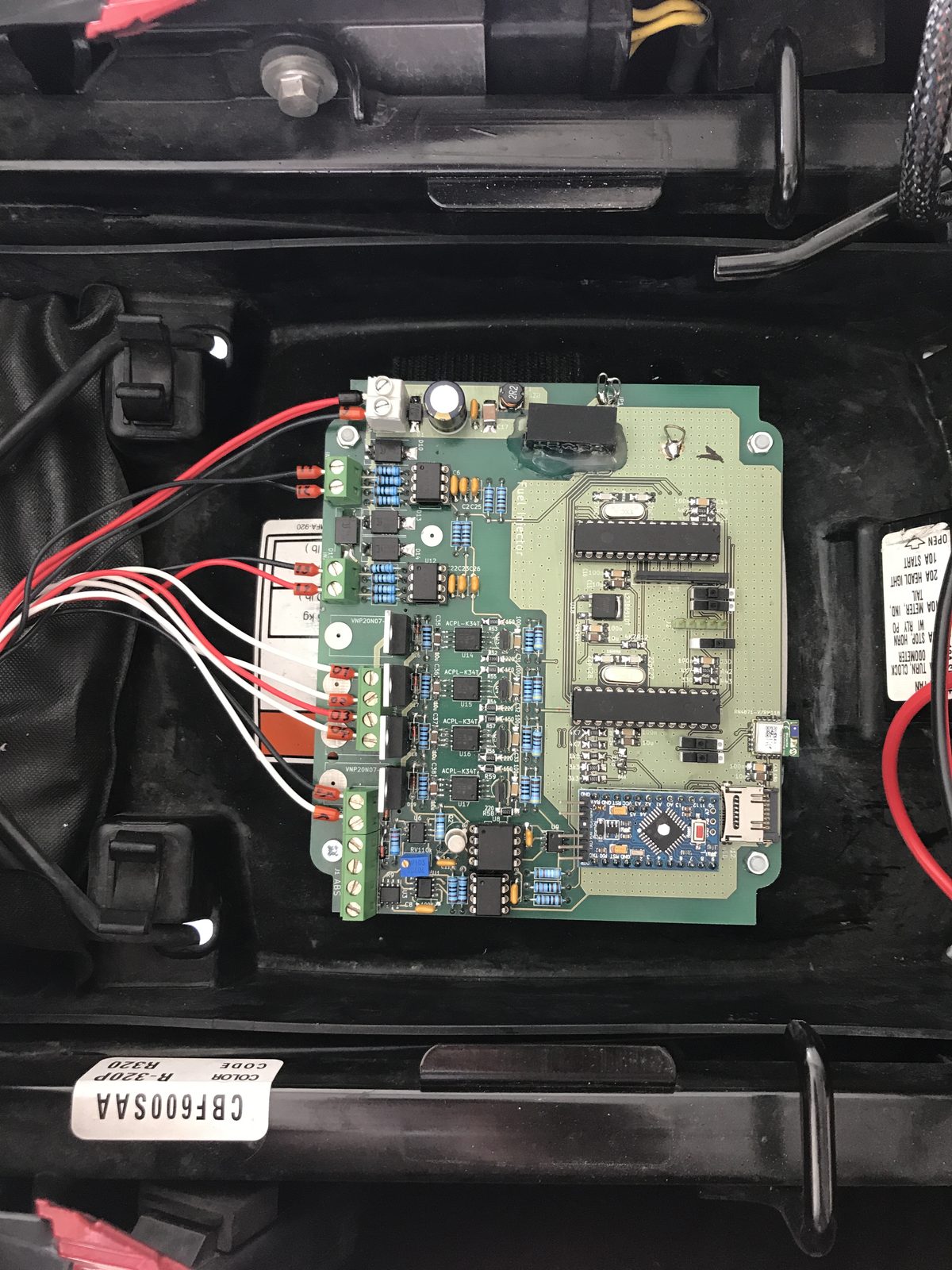 The prototype board installed in the under-seat tray of the motorcycle, wired into the bike's harness
